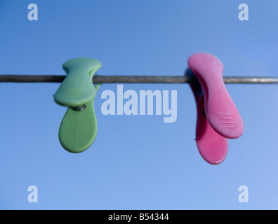 One green and one pink peg on a clothes line Stock Photo