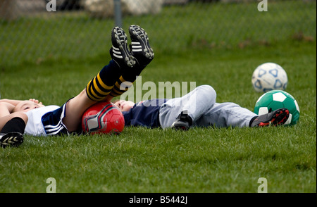 Young kids laying on the ground after a tiring soccer practice. Stock Photo