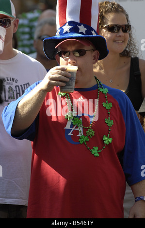 A man in a patriotic Uncle Sam style hat enjoys a beer at a street festival. Stock Photo