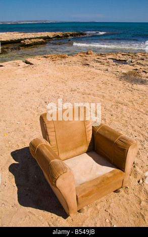 Old easy chair dumped on beach near Ayia Napa on the Mediterranean island of Cyprus EU Stock Photo