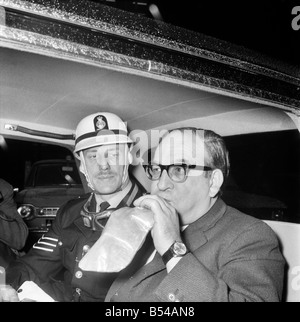 Politics. Transport. Road safety: The Minister of Transport, Mr. Fred Mulley was 'breathalysed' this morning from Police Sergeant Syd Furner, and then had a blood sample taken by experimental Lab Technician Gillian Martin as a demonstration for the Press. The Minister blowing into the bag, in the back of his car for Sergeant Syd Furner. November 1969 Z10861-002 Stock Photo