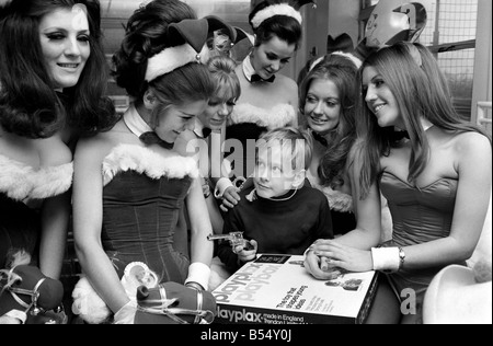 London's Playboy Club Bunny Girls, made their own private collection of £127 to donate for toys to the Gt. Ormond Street Childrens Hospital. The collection was made from 18 of the girls in the famous London Playboy Club. Today six of the girls had lunch at the hospital with the staff and visited the wards in costume to present the toys and gifts to the children Lucky Richard Scott, 7 1/2 from London is the centre of attraction at the Gt. Ormond Street Hospital when the Bunny Girls were giving out their Christmas toys. December 1969 Z12337-004 Stock Photo