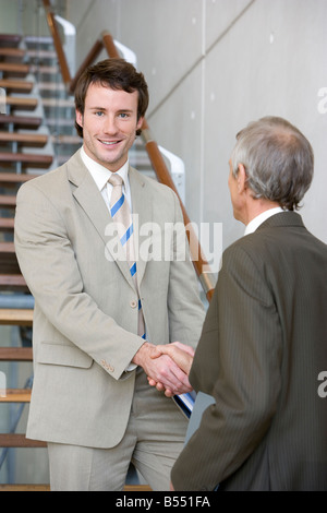 Two businessmen shaking hands on steps Stock Photo