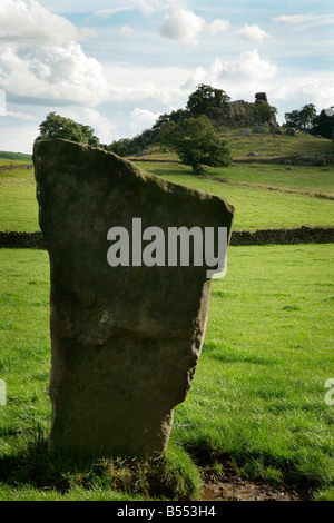 A standing stone of Harthill Moor stone circle in Derbyshire with Robin Hood's Stride in the background Stock Photo