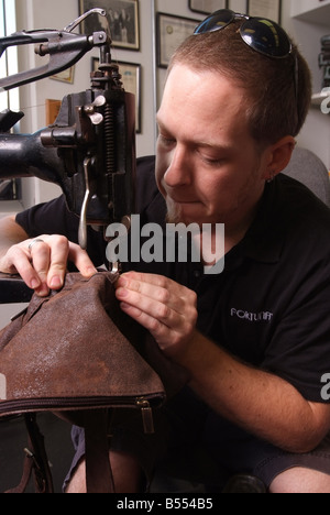 A man uses an antique Singer sewing machine to repair leather goods in a small shop in Maryland USA Stock Photo