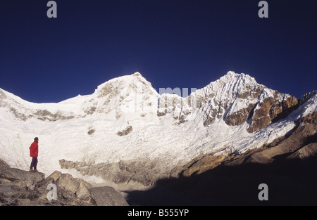 Trekker below Mt Huandoy (L to R: East and North Peaks) looking at view, Cordillera Blanca, Peru Stock Photo