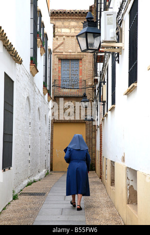 Nun walks down an empty narrow street in old Cordoba Stock Photo