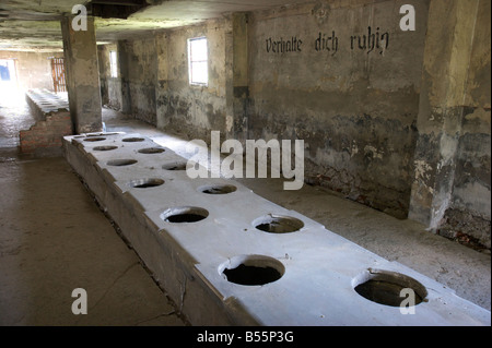 Mass toilet barrack with inscription 'Verhalte dich ruhig' in former concentration camp Auschwitz II (Birkenau) Stock Photo