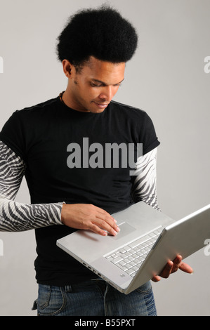 Portrait of young trendy latino man holding modern laptop computer Stock Photo