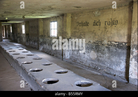 Mass toilet barrack with inscription 'Verhalte dich ruhig' in former concentration camp Auschwitz II (Birkenau) Stock Photo