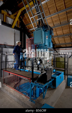 Engineer checking for oil leaks on the blade angle actuator shaft seal of turbine of small scale hydro electric power scheme Stock Photo