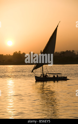 A silhouetted felucca traditional wooden sailing boat on the Nile river between Aswan and Luxor Egypt Stock Photo