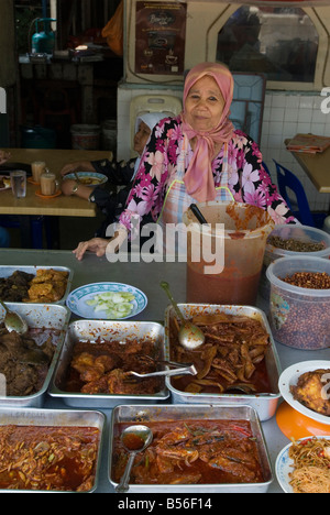 A food stall owner displays her trays of food in a food hall in the traditional Malay area of Kampung Baru, Kuala Lumpur, Malaysia Stock Photo