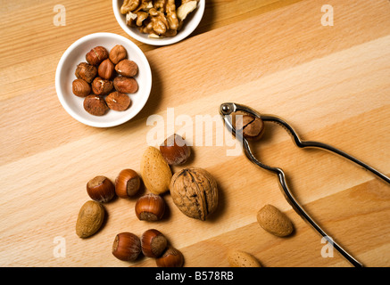 almond, walnuts, hazelnuts, nutcracker and cracked nuts in bowls Stock Photo