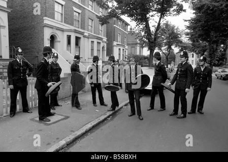 Lewisham Riot 1977 : Police officers armed with dustbin lids for shields re-group in a Lewisham side street. Following clashes between extremists on the Right and Left. The riot was sparked by a National Front march through the centre of town, which was confronted by a left wing counter demonstration. August 1977 77-04357-034 Stock Photo