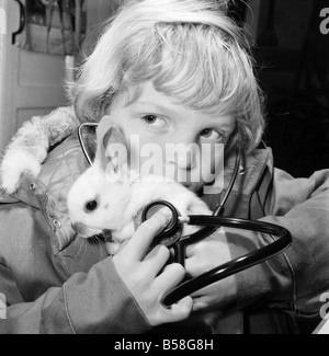 Animal: Cute: Bunny: It was a moment of tender wonderment, when a child can hear the rhythmic beat of a tiny heart. The few weeks old white rabbit at the ChildrensÍ Zoo, Crystal Palace, London is just one of a litter born there, and soon to be heading for new homes. When seven years old John Gankerseer, of Burgess Hill, Sussex was paying the park a visit with his family, he had the chance to use the stethoscope and listen for a while the life beat of little animal. The wonder of another world brought to his ears. December 1976 76-07571-006 Stock Photo