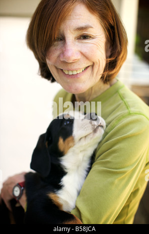 An elderly red headed woman looks pleased as punch as she picks up her new puppy for the first time. He looks pretty happy too. Stock Photo