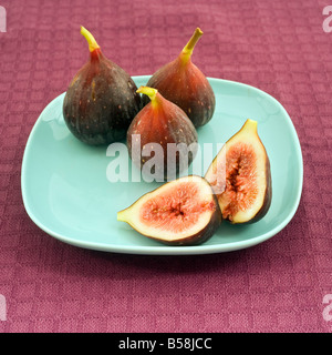 still life three whole figs and one sliced on blue plate Stock Photo
