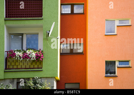 Windows balcony and satellite dish on brightly painted block of flats Miastko Poland Stock Photo