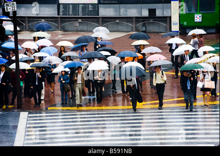 Pedestrians with umbrellas waiting at the main crossing in The Shibuya ...