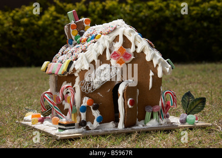 Christmas gingerbread house cake with sweets and icing decorations on a garden lawn in Queensland QLD Australia Stock Photo