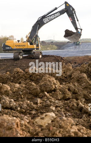 digger yellow earth moving mover dig 360 bucket scoop soil quarry quarrying equipment plant hire digging hole soil mud Stock Photo