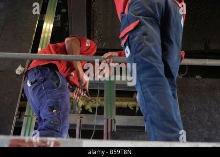 Two Airconditioning  Technicians work to renovate an existing installation. Stock Photo
