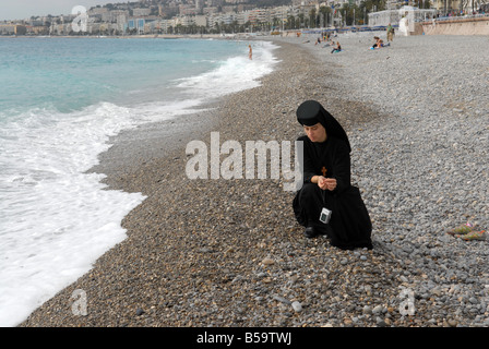 An orthodox Ukranian Nun with her digital camera on the beach in Nice in the South of France. Picture by DAVID BAGNALL Stock Photo