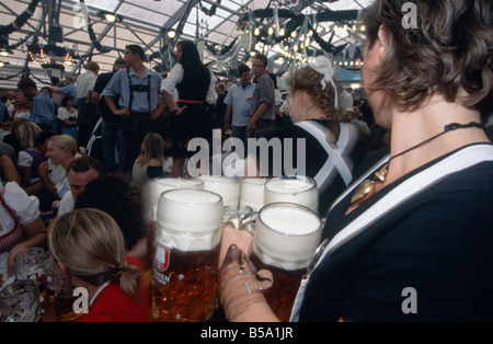 Oktoberfest Annual beer festival Huge hall Waitress woman carrying tray of huge steins beer jugs glasses MUNICH GERMANY Stock Photo