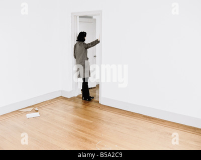 Woman Leaning Against Doorframe In Empty Apartment Stock Photo
