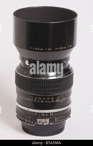 A well used Nikon 105mm f2.5 ai Nikkor telephoto manual focus lens with  lens hood attatched for Nikon 35mm slr film cameras Stock Photo