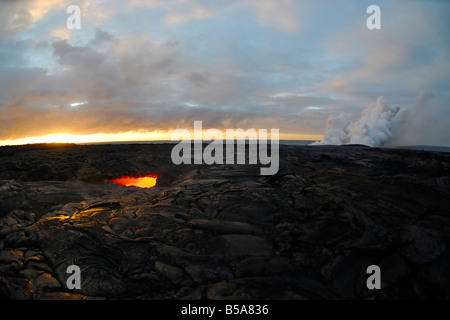 Skylight and flowing lava at sunrise Waikupanaha ocean entry lava flow area Stock Photo