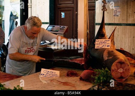 Fishmonger in Ballarò market, Palermo, Sicily cuts up a tuna fish for a customer Stock Photo