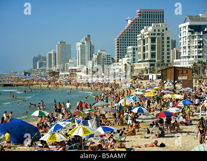Crowds of tourists on the beach with tall seafront buildings, at Tel Aviv, Israel, Middle East Stock Photo