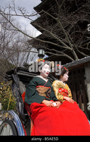 Two geishas in traditional dress posing on a rickshaw, Higashiyama neighbourhood, Kyoto, Kansai, Honshu, Japan Stock Photo