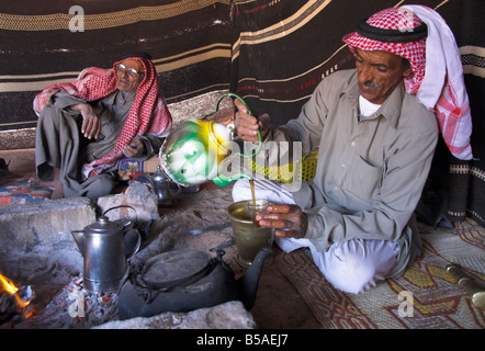 Bedouin man wearing keffiyah pouring tea in Bedouin camp, Wadi Rum, Jordan, Middle East Stock Photo