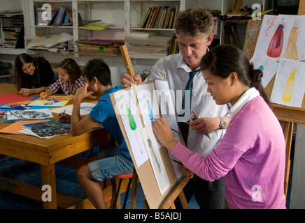 School Art Class fashion design with teacher and teenage girl pupil working on her fashion design clothing collection drawings in school art classroom Stock Photo