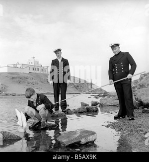 The lighthouse keepers and their families go about their daily duties around The Strathy Point Lighthouse. These include cleaning the lamp, maintaining the foghorn and looking after the garden. 1960 A797-003 Stock Photo