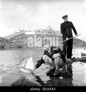 The lighthouse keepers and their families go about their daily duties around The Strathy Point Lighthouse. These include cleaning the lamp, maintaining the foghorn and looking after the garden. 1960 A797-009 Stock Photo