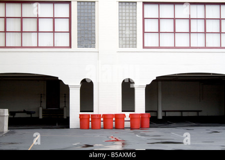Six orange barrels in front of a white building between two garages Stock Photo