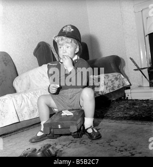 Child playing, pretending to be a policeman: Kenneth Knowles of Manchester seen here enjoying his milky bar white chocolate bar. September 1957 Stock Photo