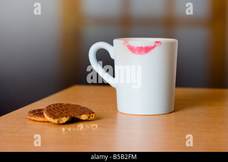 Coffee mug with lipstick mark and chocolate biscuits on table Stock Photo