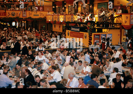 Oktoberfest Annual beer festival Huge hall Lights on ceiling People at tables drinking from steins litre jugs MUNICH GERMANY Stock Photo
