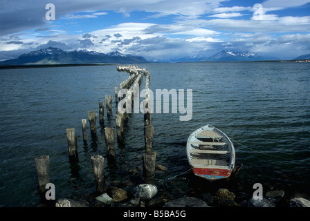 Fishing boat and wooden piles, the remains of an old jetty / pier, in Last Hope Sound, Puerto Natales, Patagonia, Chile Stock Photo