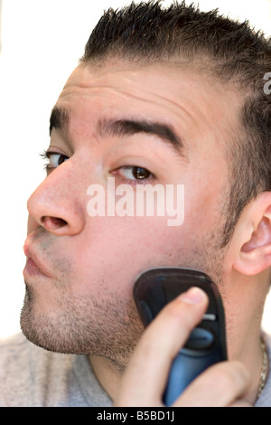 A closeup of a young man shaving his beard off with an electric shaver Stock Photo