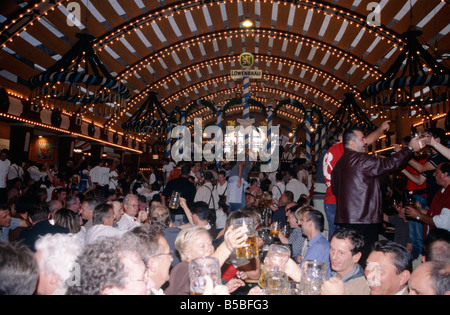 Oktoberfest Annual beer festival Huge hall Lights on ceiling People drinking from steins litre beer mugs MUNICH GERMANY Stock Photo
