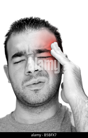 A young man grasps his head in anguish from pain or even stress Stock Photo