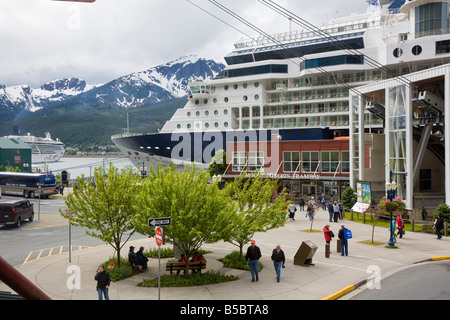 Infinity cruise ship docked between snow capped mountains and the Mount Roberts Tramway in Juneau, Alaska Stock Photo