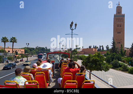 The top deck of an organised tourist bus tour around Marrakesh with the Koutoubia Mosque minaret on the right. Stock Photo