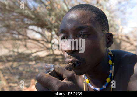 A man of the Hadza tribe smoking a pipe with marijuana Lake Eyasi Tanzania Stock Photo